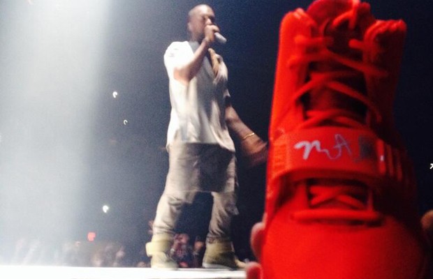 Kanye West 在演唱會進行間幫一位粉絲在他的 “Red October” Nike Air Yeezy 2s 上簽名